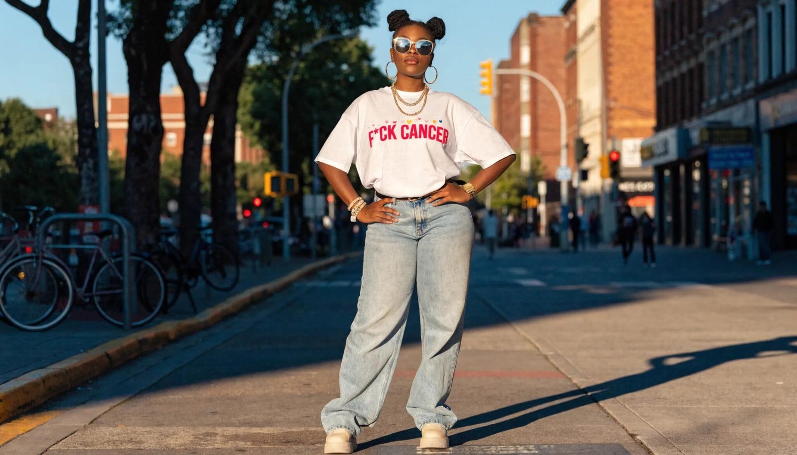Woman with tattoos wearing a white t-shirt featuring a pink F*CK CANCER graphic